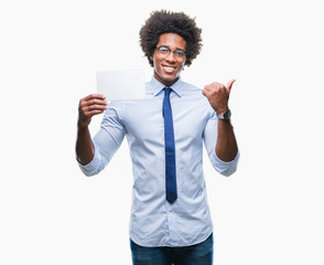 Afro american man holding blank card over isolated background pointing and showing with thumb up to the side with happy face smiling
