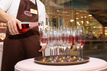 Waiter pours pink champagne into beautiful glasses