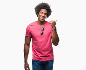 Afro american man over isolated background smiling with happy face looking and pointing to the side with thumb up. © Krakenimages.com