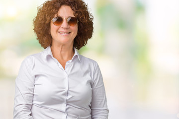 Beautiful middle ager senior business woman wearing sunglasses over isolated background with a happy and cool smile on face. Lucky person.