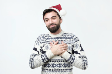 Happy friendly man in red christmas hat being content to hear compliment from his girlfriend,...