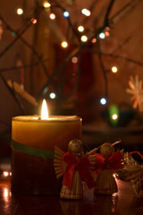 Two straw angels stand in a lit candle. Christmas angels, decoration.