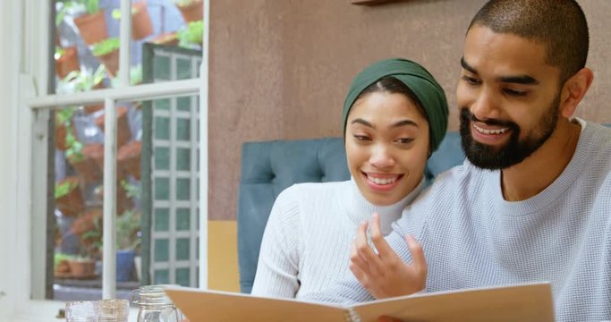 Couple discussing menu card in cafe 4k