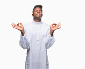Young arabic african man wearing traditional djellaba over isolated background relax and smiling with eyes closed doing meditation gesture with fingers. Yoga concept.