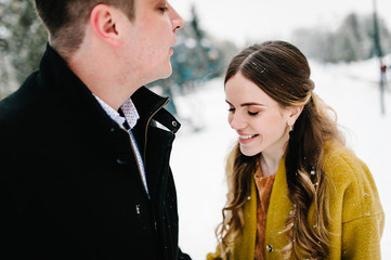 Happy couple hugging and laughing near christmas tree, outdoors in winter. Man and woman, season, love and leisure concept.
