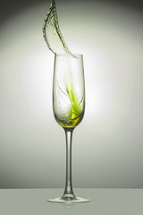 Transparent glass with a yellow jet of liquid up, close-up