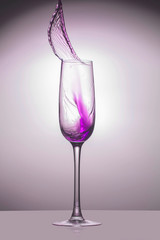 Transparent glass with a violet jet of liquid up, close-up