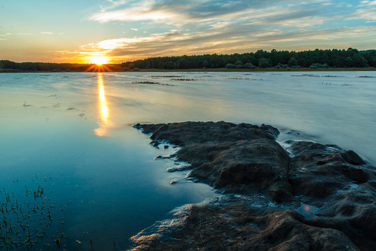 el sol refleja sobre el lago un rayo de luz, que simula una llama de fuego.