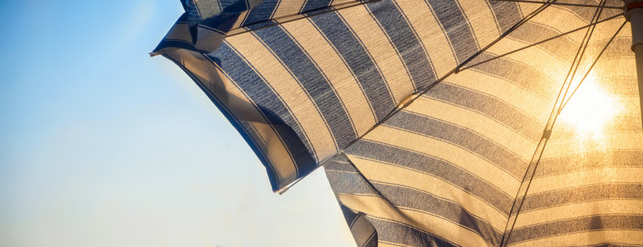 Umbrella and sun in front at sunset