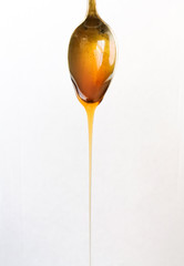 close-up silvery and vintage spoon with honey falling, on white background
