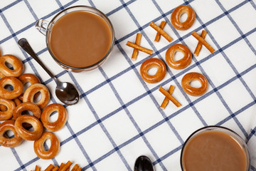 Noughts and crosses using biscuits and two cups of coffee.