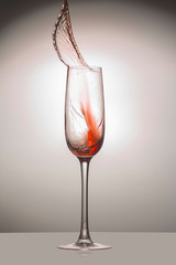 Transparent glass with a red jet of liquid up, close-up