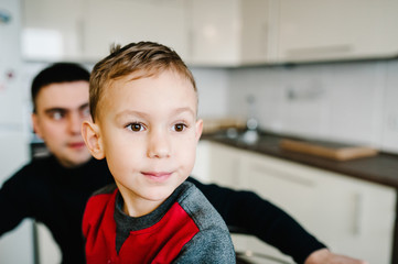 Family, eating and people concept - happy father and son having breakfast in the kitchen at home.