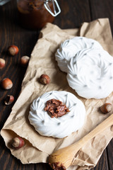 Portion of mini Pavlova meringue cake decorated with salted caramel sauce or chocolate paste over old brown wooden background.