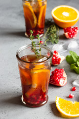 Cold lemonade or festive cocktail with pomegranate, mint and orange. Grey concrete background. Copy space.