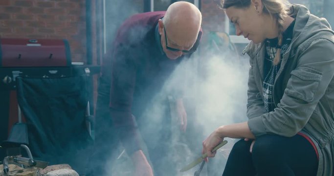 Young woman and her father are cooking food on the barbecue