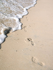 Traces of a man on the sand, on the ocean washed off with sea foam
