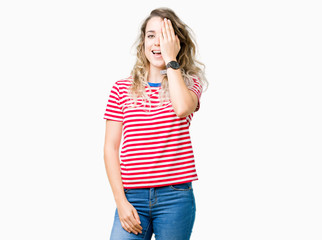 Fototapeta premium Beautiful young blonde woman over isolated background covering one eye with hand with confident smile on face and surprise emotion.