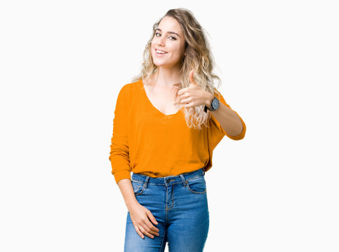 Beautiful young blonde woman over isolated background doing happy thumbs up gesture with hand. Approving expression looking at the camera with showing success.