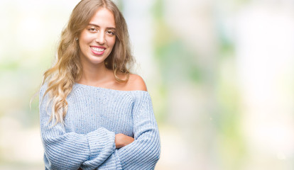 Beautiful young blonde woman wearing winter sweater over isolated background happy face smiling with crossed arms looking at the camera. Positive person.