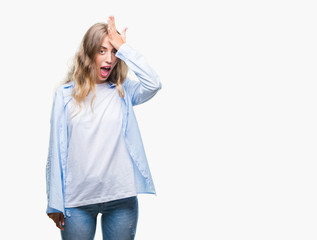 Beautiful young blonde woman over isolated background surprised with hand on head for mistake,...