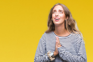 Beautiful young blonde woman wearing stripes sweater over isolated background begging and praying with hands together with hope expression on face very emotional and worried. Asking for forgiveness