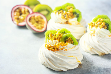 Homemade cake Pavlova with whipped cream, fresh kiwi and passion fruit.