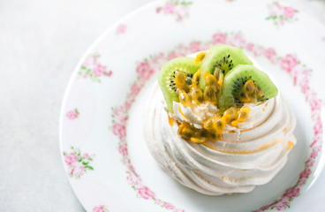 Homemade cake Pavlova with whipped cream, fresh kiwi and passion fruit.
