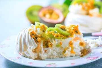 Homemade cake Pavlova with whipped cream, fresh kiwi and passion fruit.