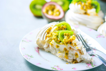 Homemade cake Pavlova with whipped cream, fresh kiwi and passion fruit.