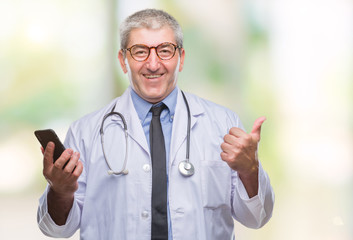 Handsome senior doctor man texting sending message using smarpthone  over isolated background pointing and showing with thumb up to the side with happy face smiling