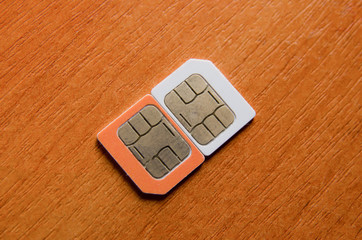 Two micro orange and white mini SIM card with copyspace. Close. Macro photography. brown background