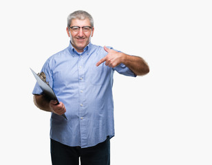 Handsome senior inspector man holding clipboard over isolated background with surprise face pointing finger to himself