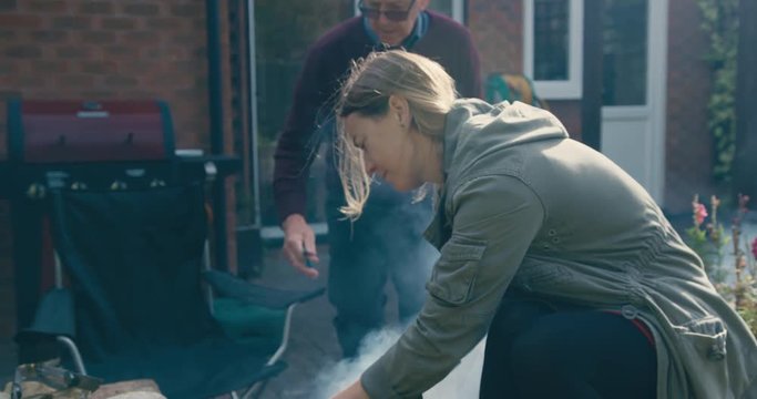 Young woman and her father are cooking on a smoking barbecue