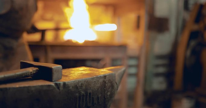 Blacksmith gets metal from the furnace and knocks on it with a hammer. Close-up