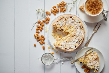 Horizontal shot of a whole round delicious apple cake tart with almond flakes served on wooden...
