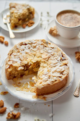 Vertical shot of a whole round delicious apple cake tart with almond flakes served on wooden table....