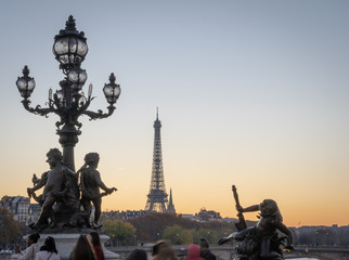 Obraz premium Paris, France - 11 18 2018: panoramic view of Paris and the Eiffel Tower from the Alexander III bridge with floor lamp at sunset