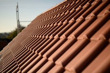 Pfannendach Panorama einer roten Dacheindeckung aus Dachziegeln mit Himmel. Bedachung als fertige Arbeit am Dach. Baustellen Gebäude in der Stadt.