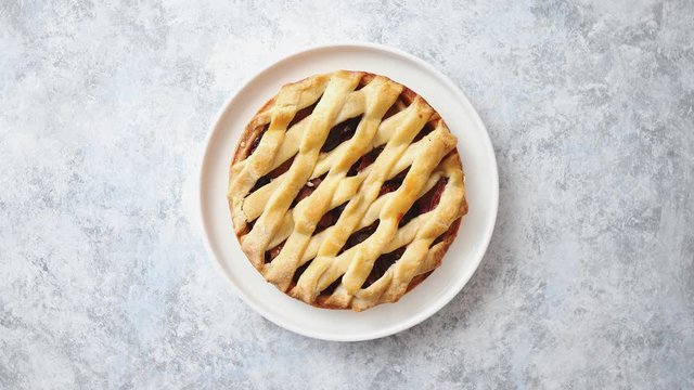 Freshly baked homemade plum cake tart served on white ceramic nordic plate. On stone background. With a copy space for text.