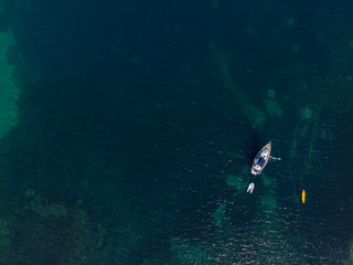 White sailing ship yacht at sea in shallow water near shore. Aerial drone view of sailboat. View from above.