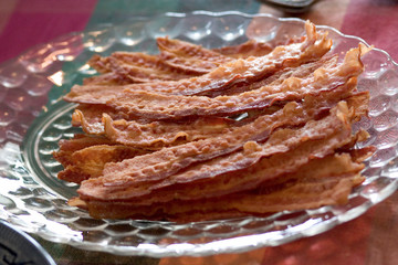 Strips of brown bacon on a plate.