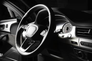 Black multifunctional leather steering wheel with gearshift paddles. In the cabin of a luxury SUV, dashboard, engine start button