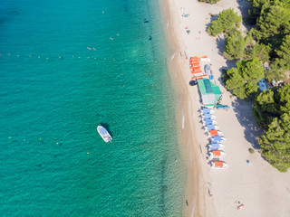 Drone aerial view of sea shore, sandy beach and blue water. Boat near beach with lot of sunshades