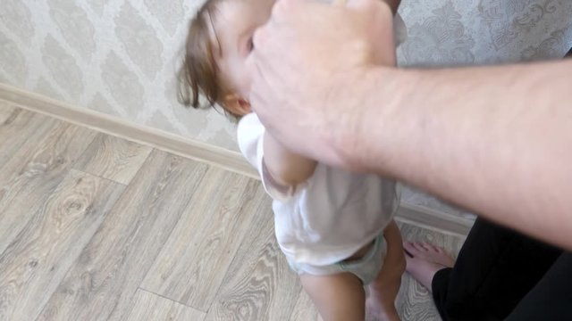 small child holds his dad with his hands. Kids jumps and laughs, plays with dad.
