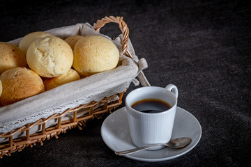 Brazilian homemade cheese bread, AKA 'pao de queijo' in a rustic basket and a cup of coffee