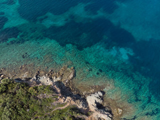 Drone aerial view of sea shore on stones and blue water
