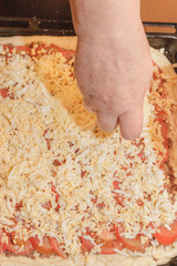 Cooking pizza pie with meat and vegetables under cheese