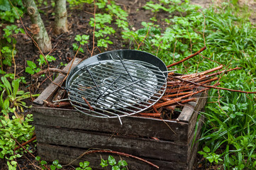 Holzkohlengrill mit Brennholzkiste im Regen