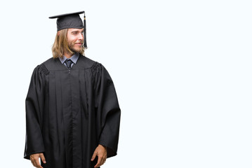Young handsome graduated man with long hair over isolated background smiling looking side and...